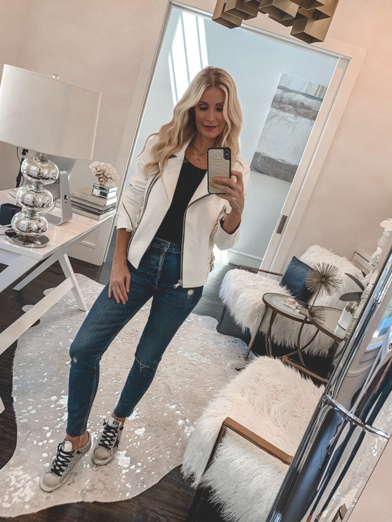 Style influencer wearing a white leather jacket and denim with sneakers 