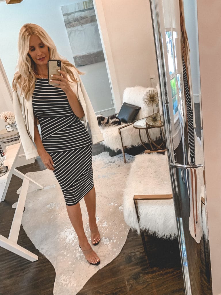 Dallas style influencer wearing a black and white striped midi dress and a white leather jacket