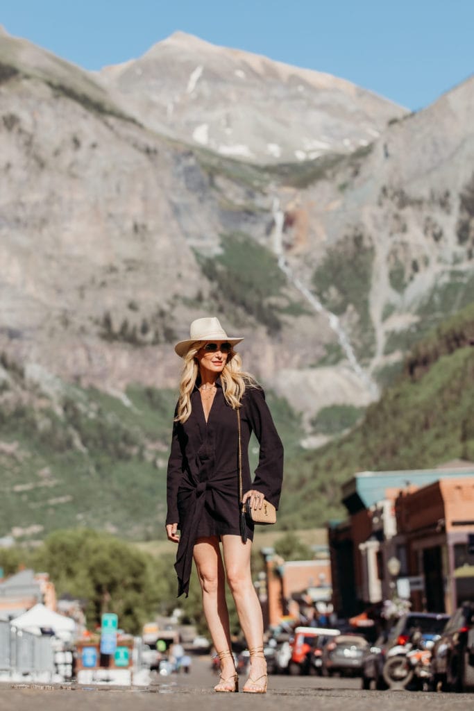 Blogger in the mountains wearing a black summer sundress and gold sandals 