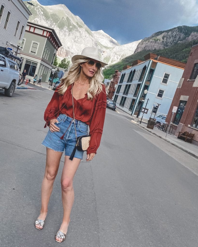 Dallas fashion blogger wearing denim shorts and a rust summer top 
