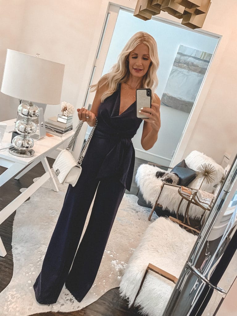 Dallas blogger wearing a navy jumpsuit and white handbag