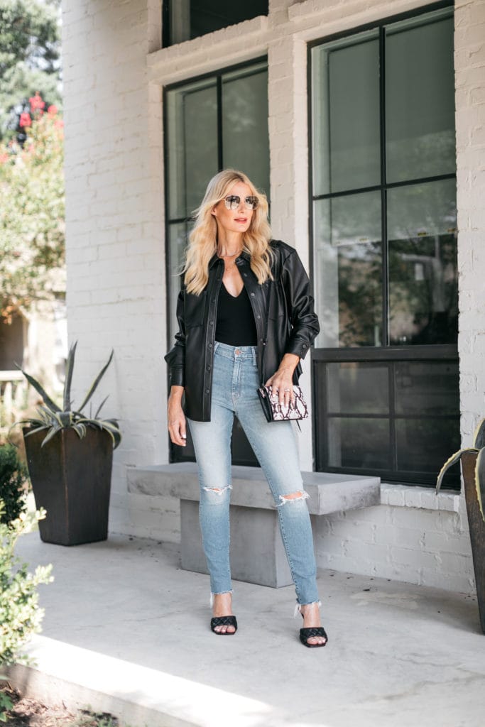Dallas blogger wearing a black leather shirt jacket and faded blue jeans
