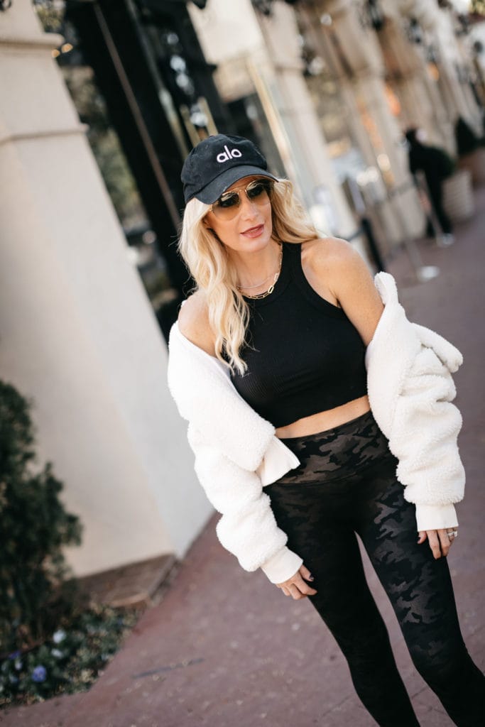 Dallas fashion blogger wearing a black workout bra and an Alo fitness hat