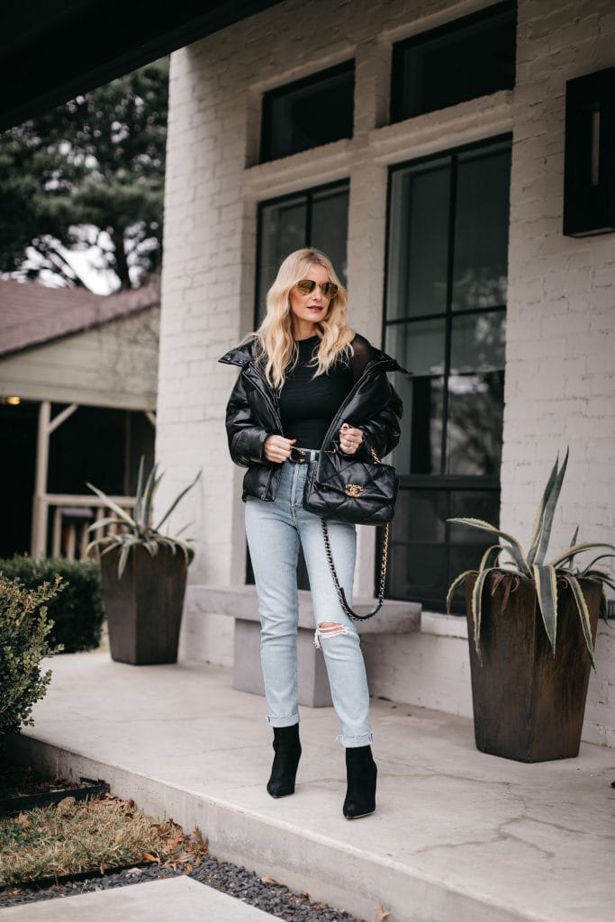Fashion blogger wearing a black puffer jacket and light wash denim with black booties