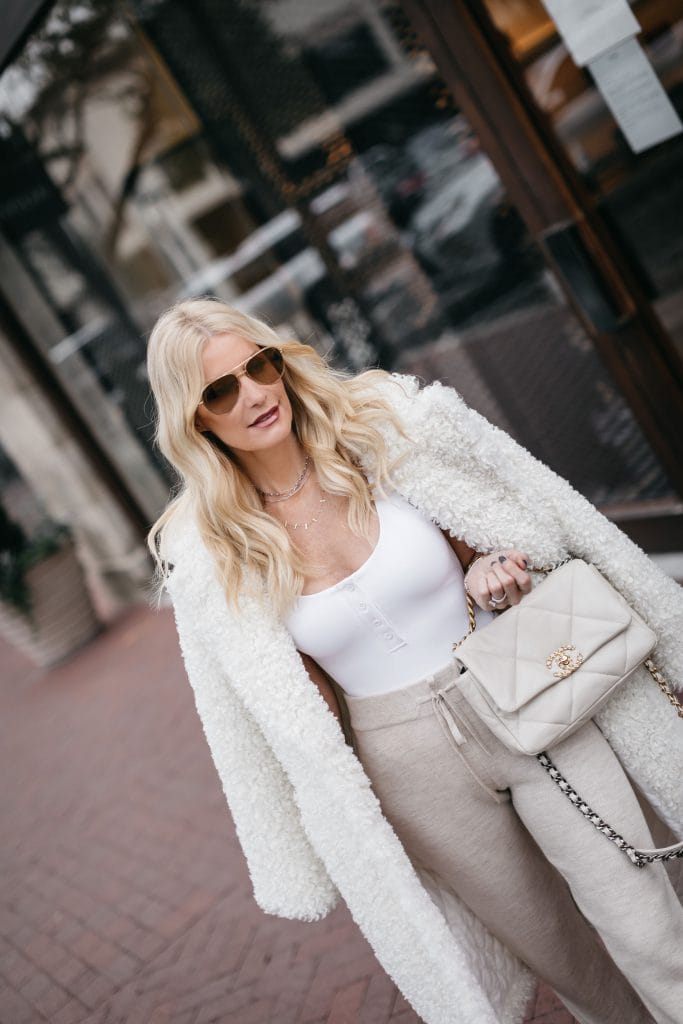 Dallas style blogger wearing a white teddy coat and a Chanel handbag with joggers