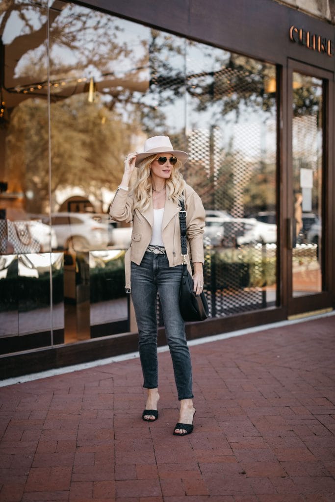 Style blogger wearing a neutral Moto jacket and black jeans with black heels and a hat