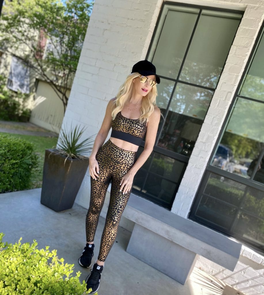 So Heather Blog wearing a metallic leopard workout set and a black hat with black tennis shoes