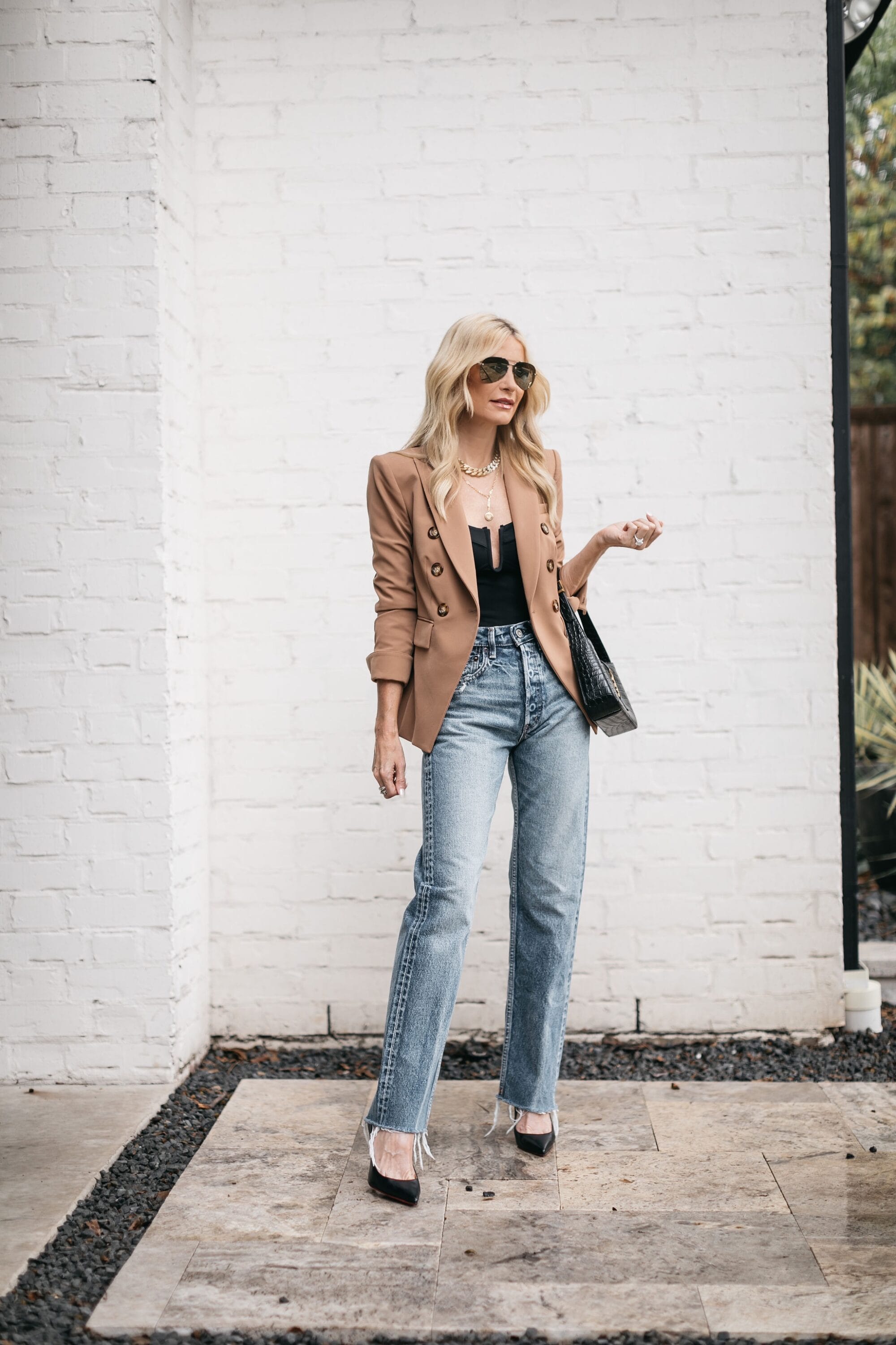 woman over 40 wearing black scuba bodysuit, veronica beard camel blazer and Ashley jeans with black heels and handbag to show top sellers in August.