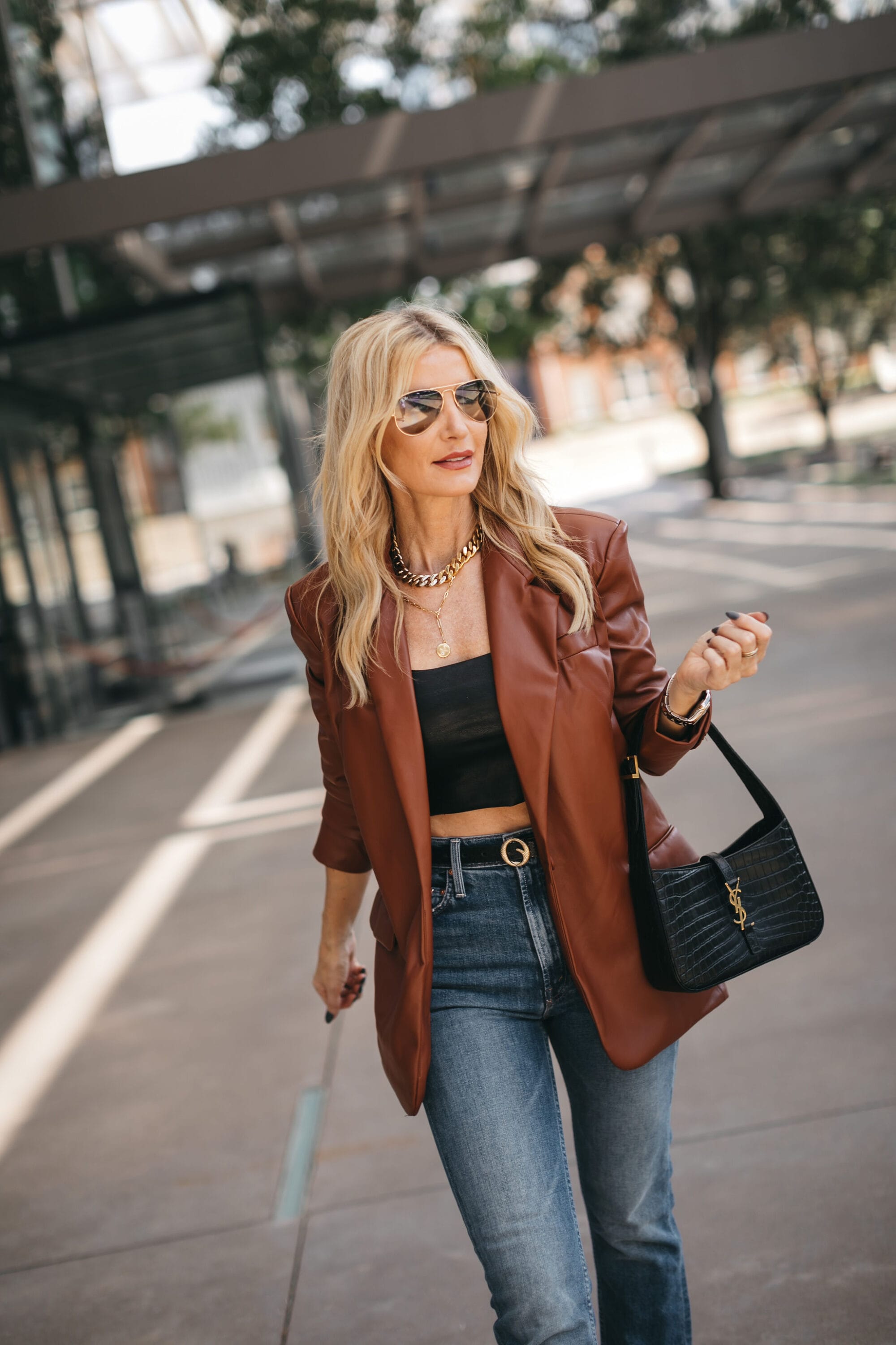 fashion influencer over 40 wearing oversize faux leather blazer, jeans and a black crop top.