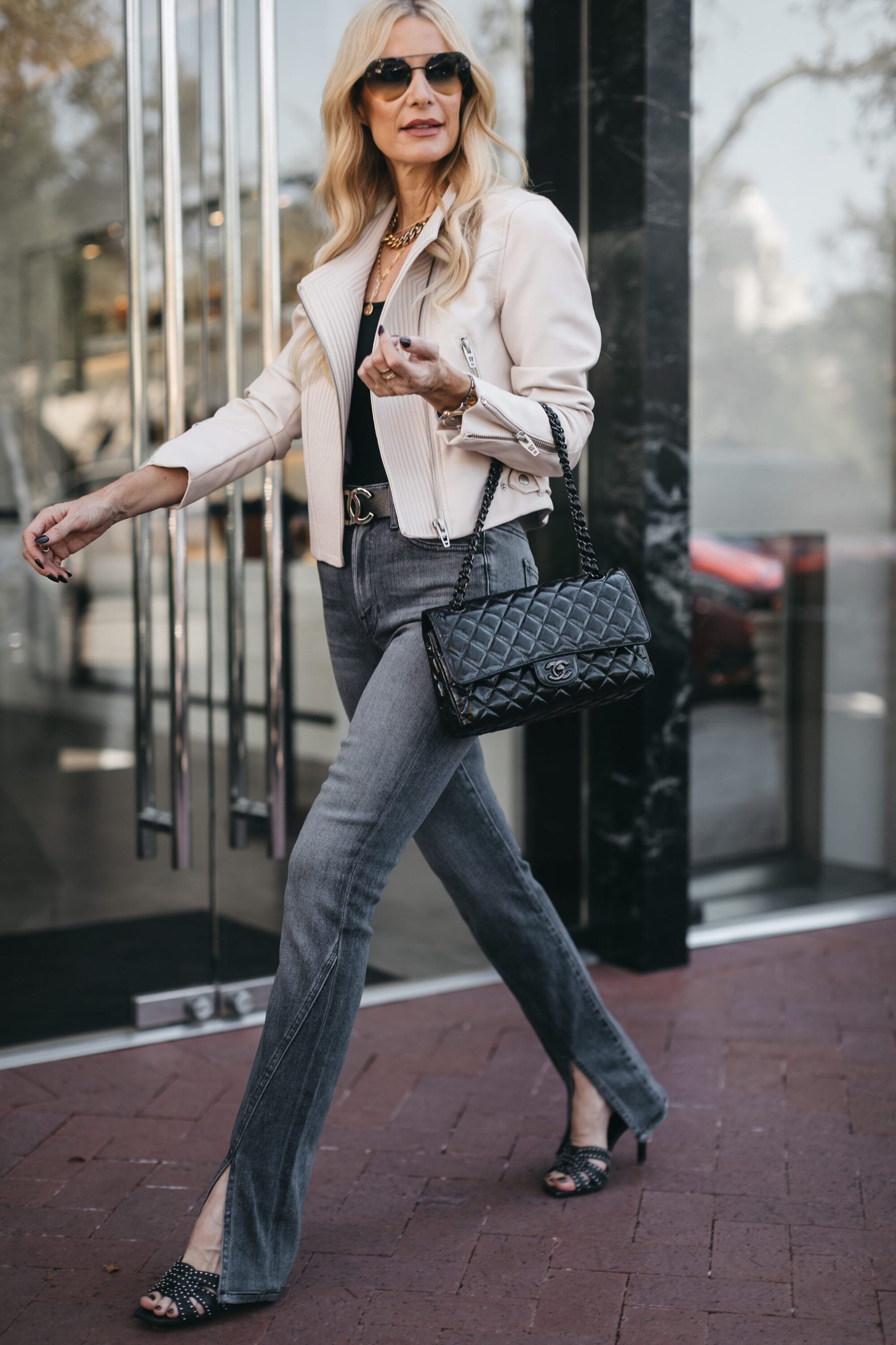 Woman Over 40 wearing on of October's best sellers - split-hem jeans with a black bodysuit and faux leather jacket.