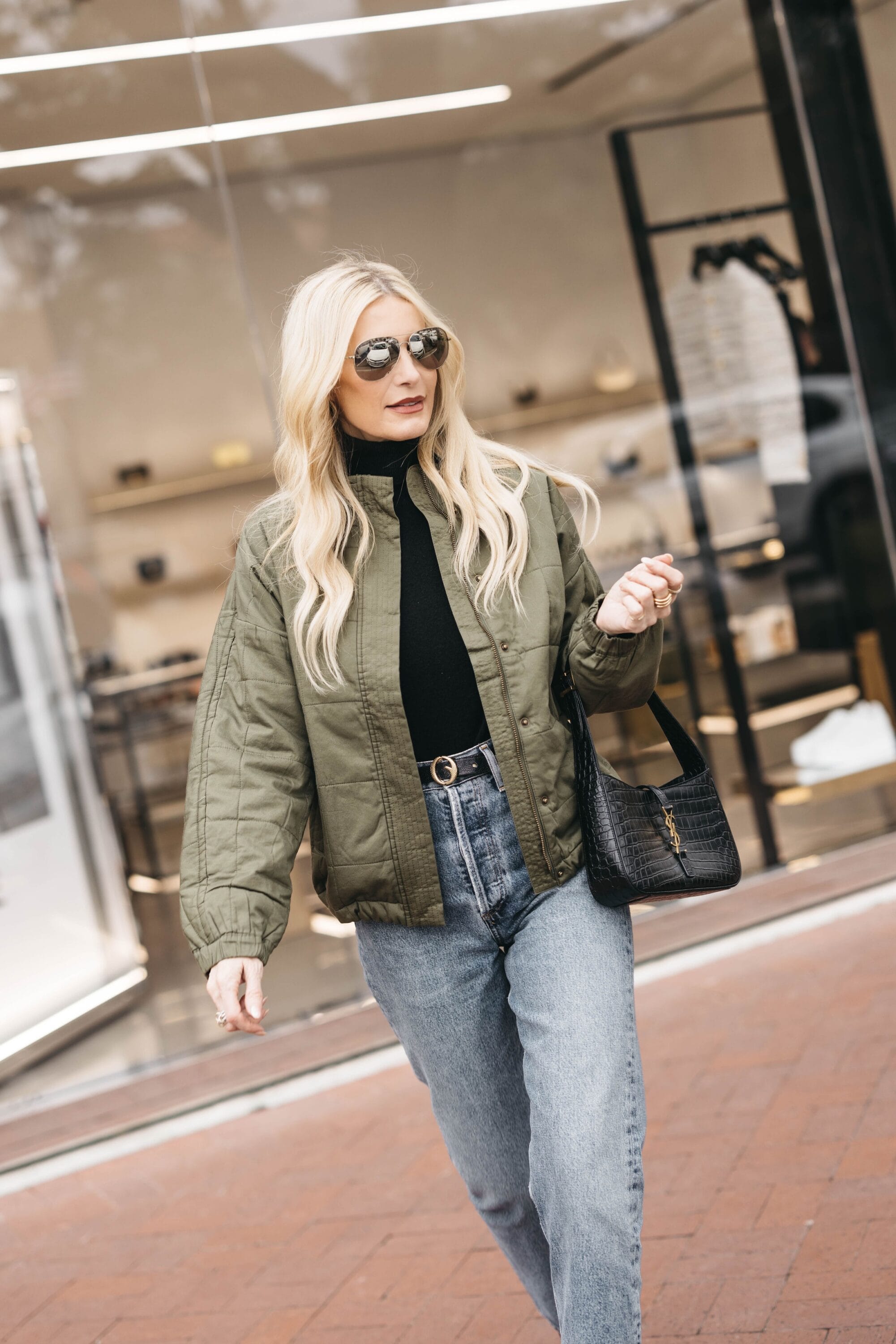 Over 40 fashion blogger from Dallas wearing Agolde 90's pinch waist jeans as one of the top denim trends of 2023 with green utility jacket and black mockneck top.