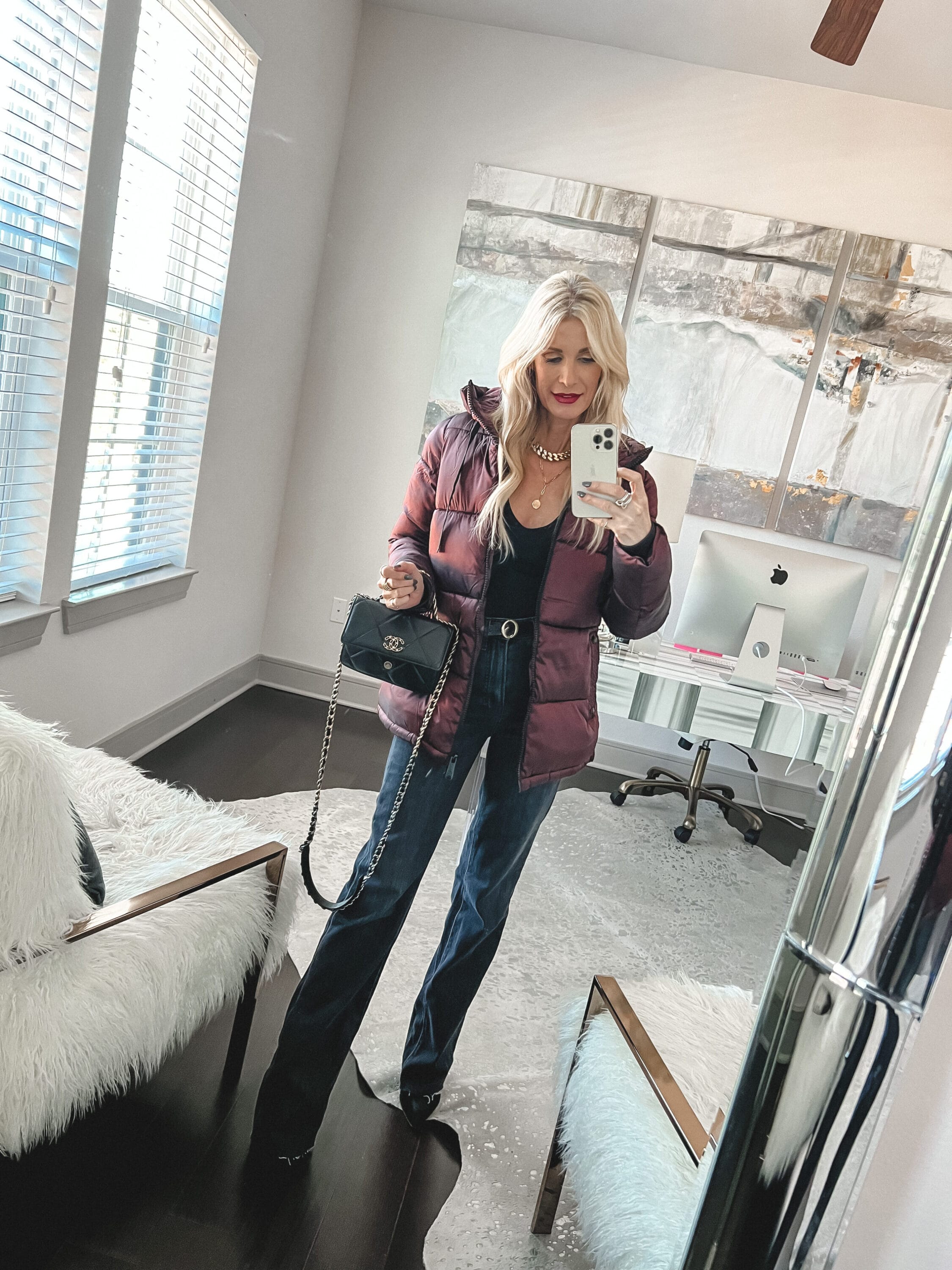 Over 40 fashion influencer wearing wine colored puffer jacket with black vintage jeans and black heels in a featured look found in the winter coat edit.