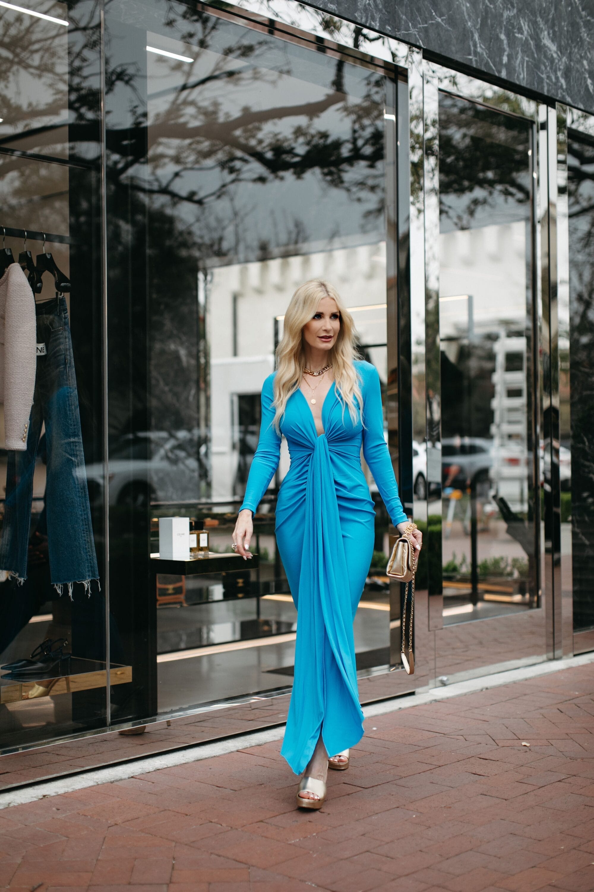 Over 40 Dallas woman wearing azure blue midin dress with gold platform heels.