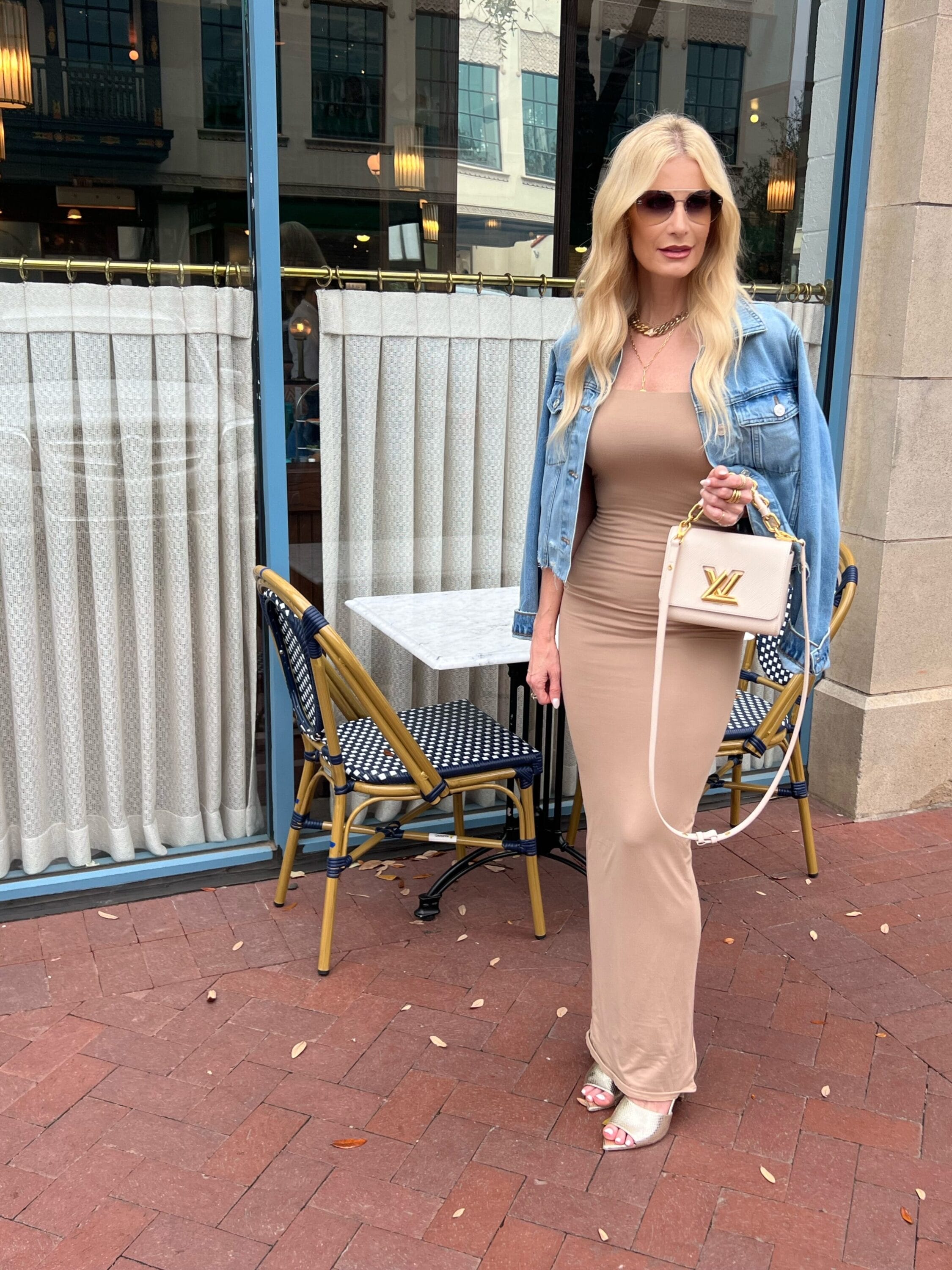 Over 40 fashion influencer wearing frame denim jacket with beige maxi dress as one of 4 options for how to style a denim jacket.
