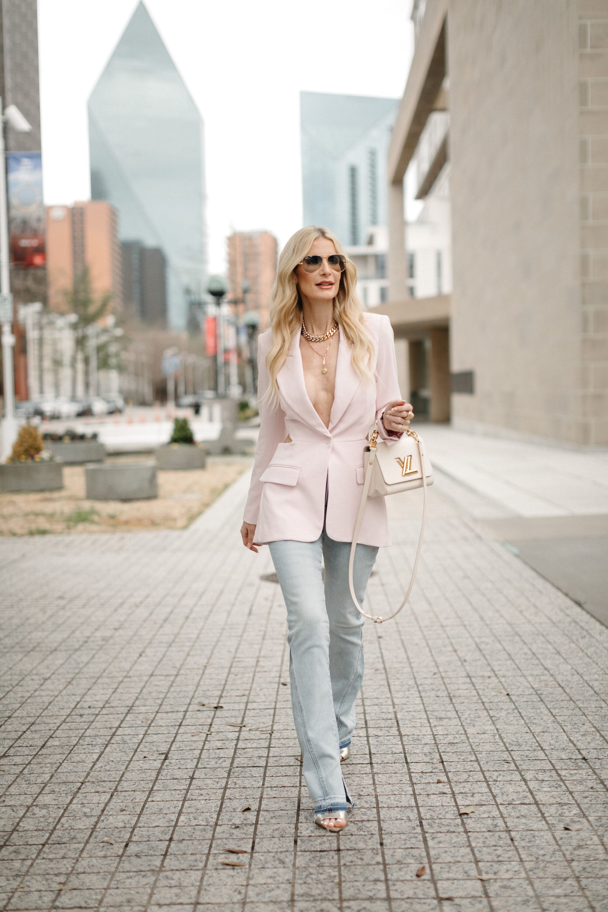 Dallas woman over 40 wearing split-hem light wash jeans fro Express with pink cut-out back blazer.