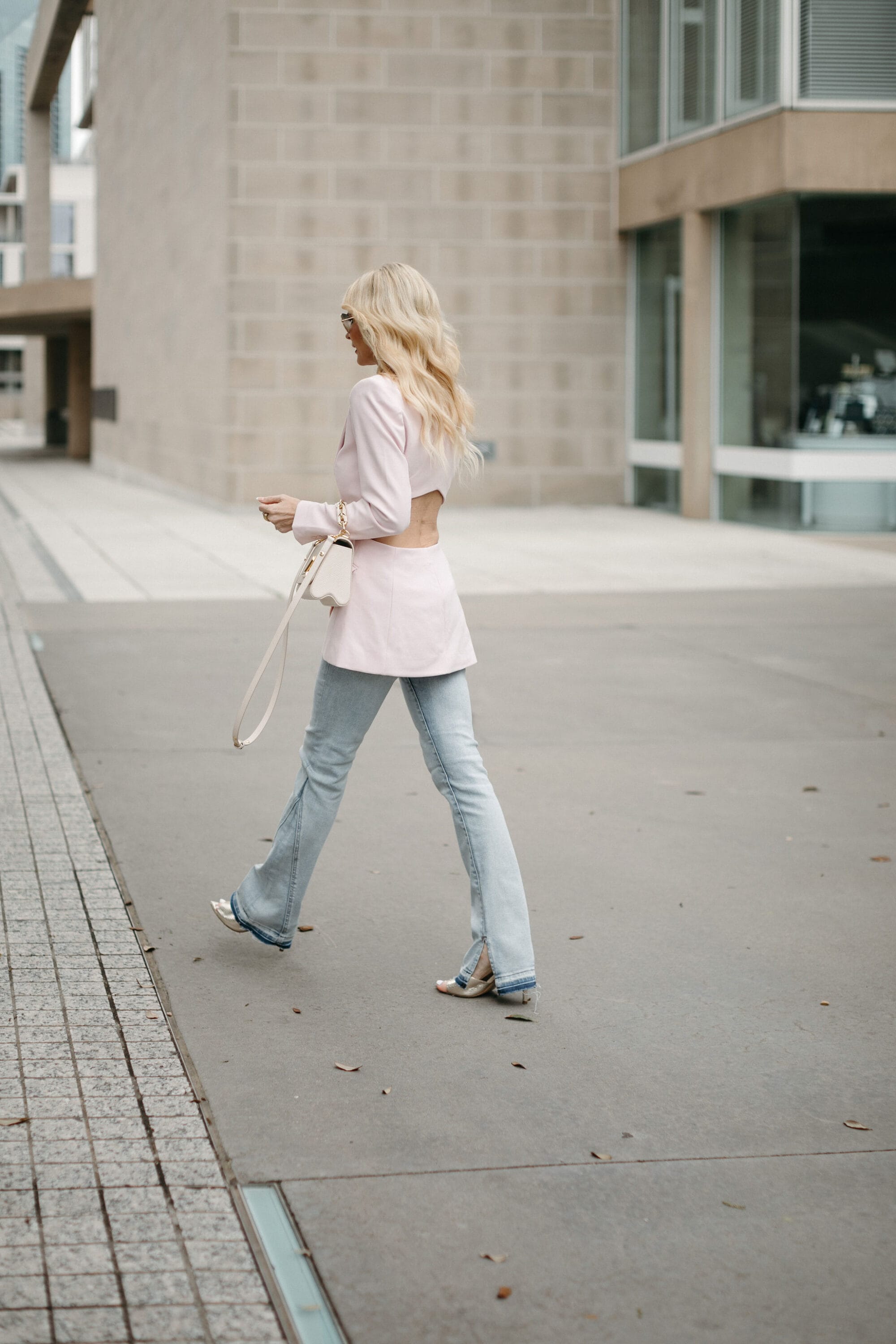 Dallas woman over 40 wearing cut-out blazer with light wash split-hem jeans.