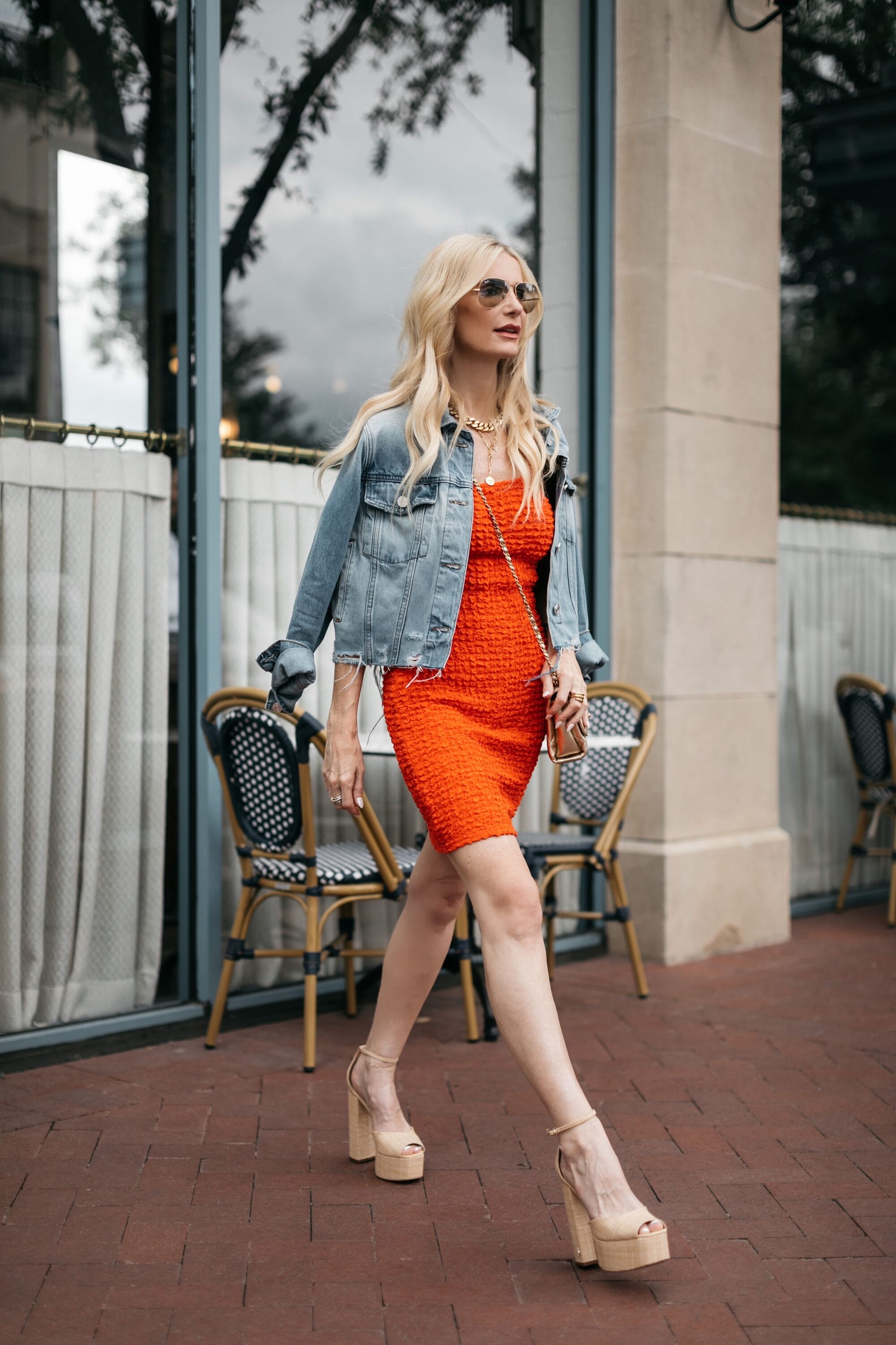 Dallas fashion blogger wears a orange dress with a cropped denim jacket as one of the hottest summer trends of 2023.