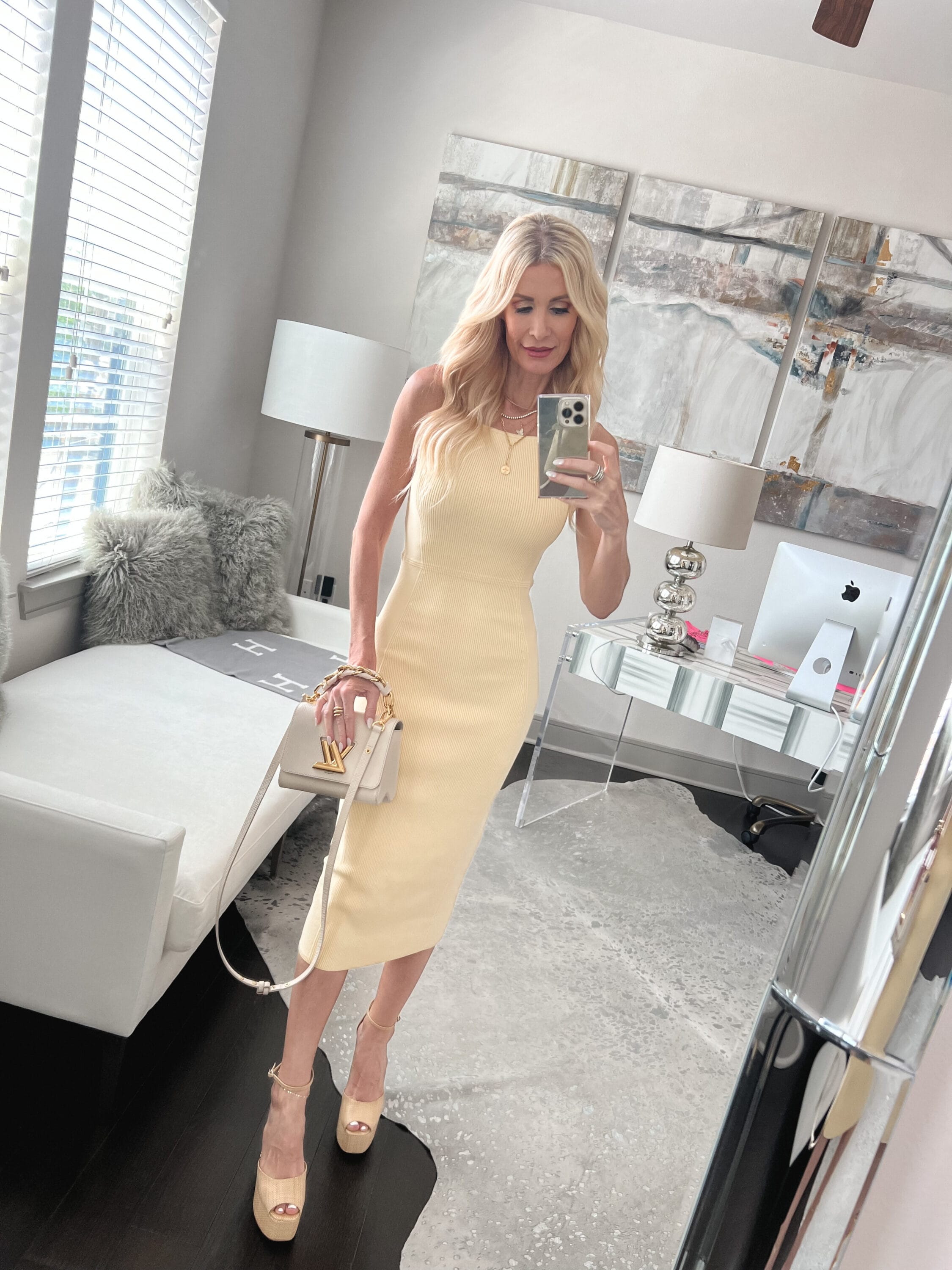 Over 40 fashion icon wears a pastel yellow midi dress with trending platform heels.