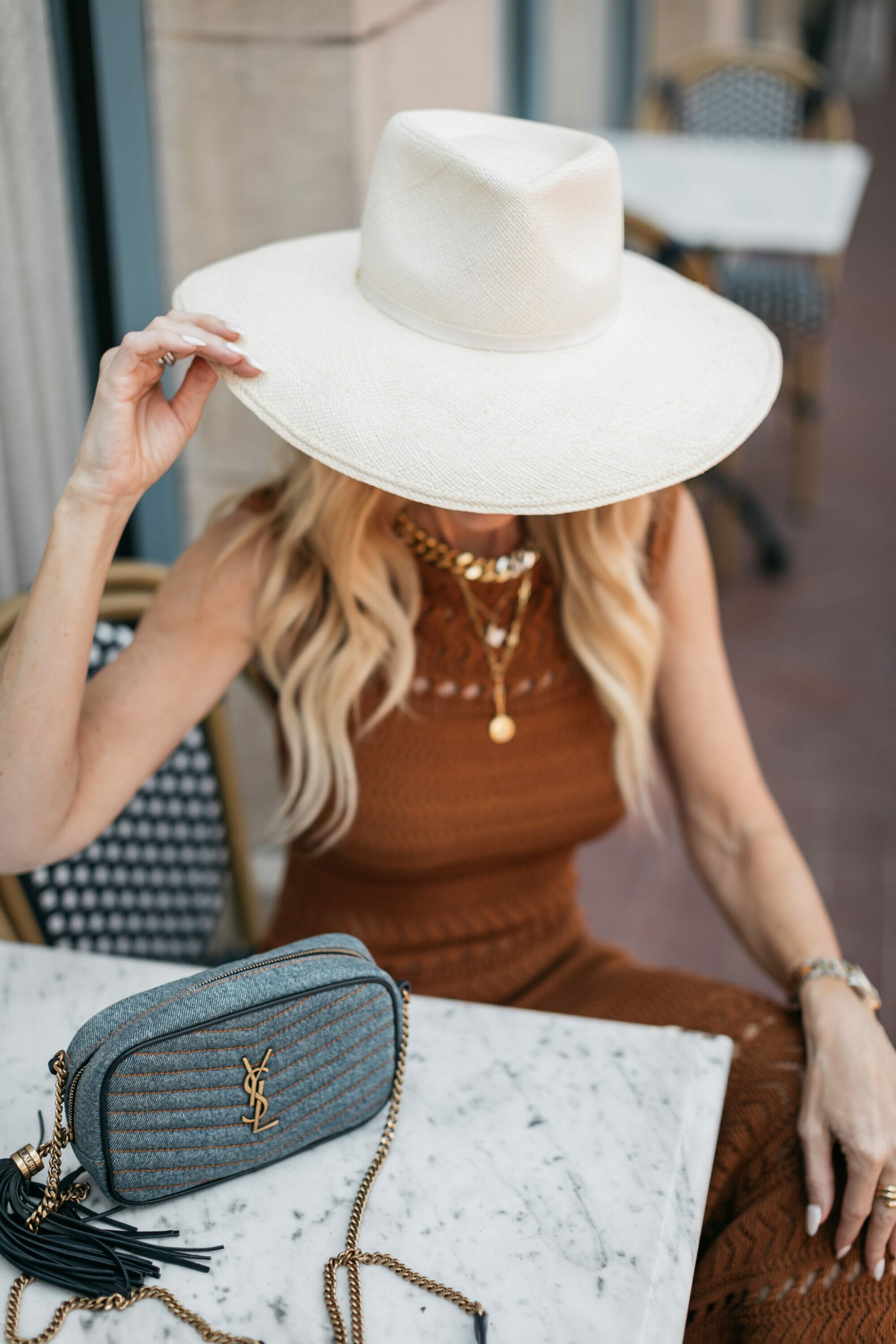 Over 40 fashion blogger wearing white sunhat with brown crochet dress and layered necklaces.
