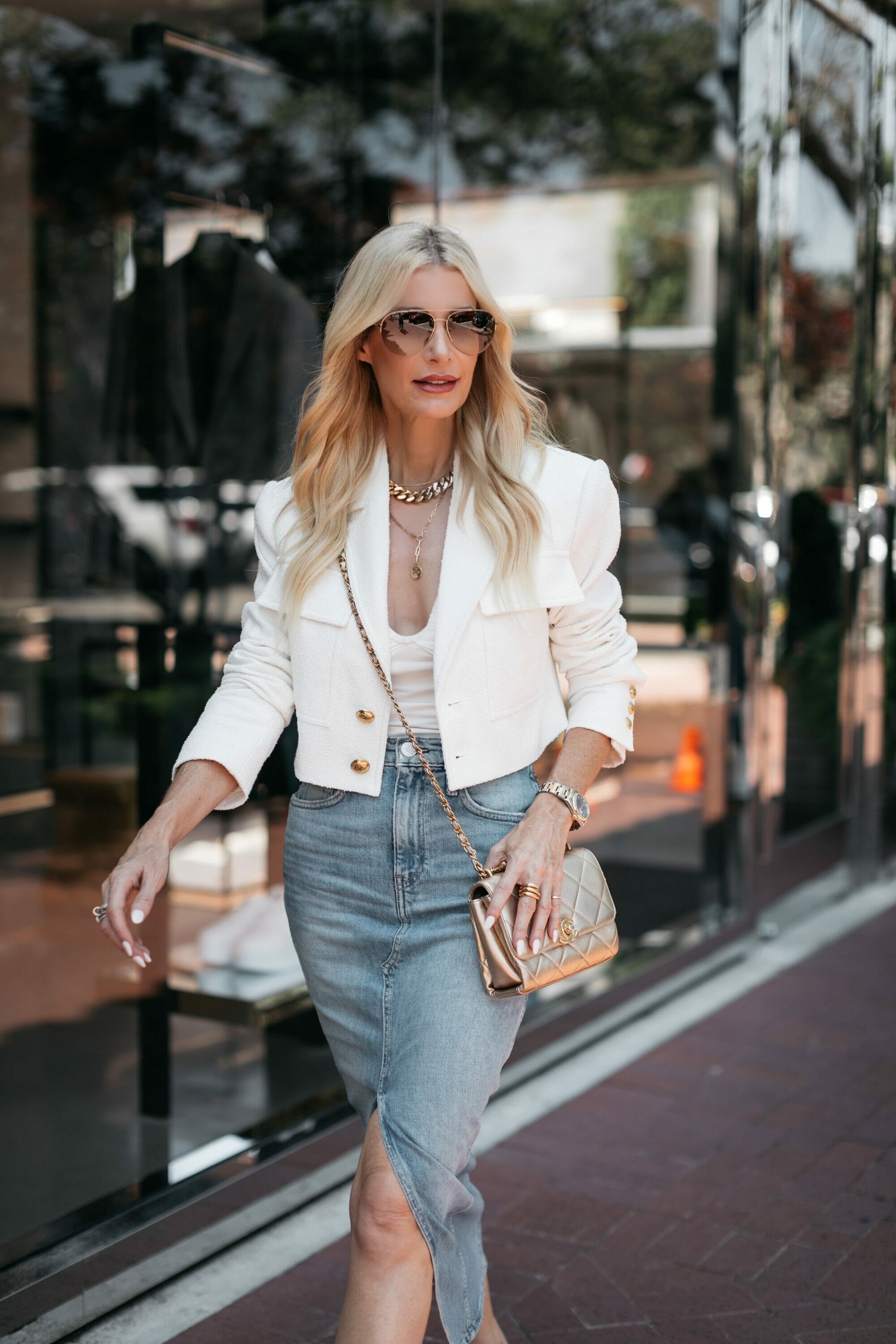 Over 40 Dallas fashion stylist wearing white cropped blazer with denim midi skirt and gold accessories.