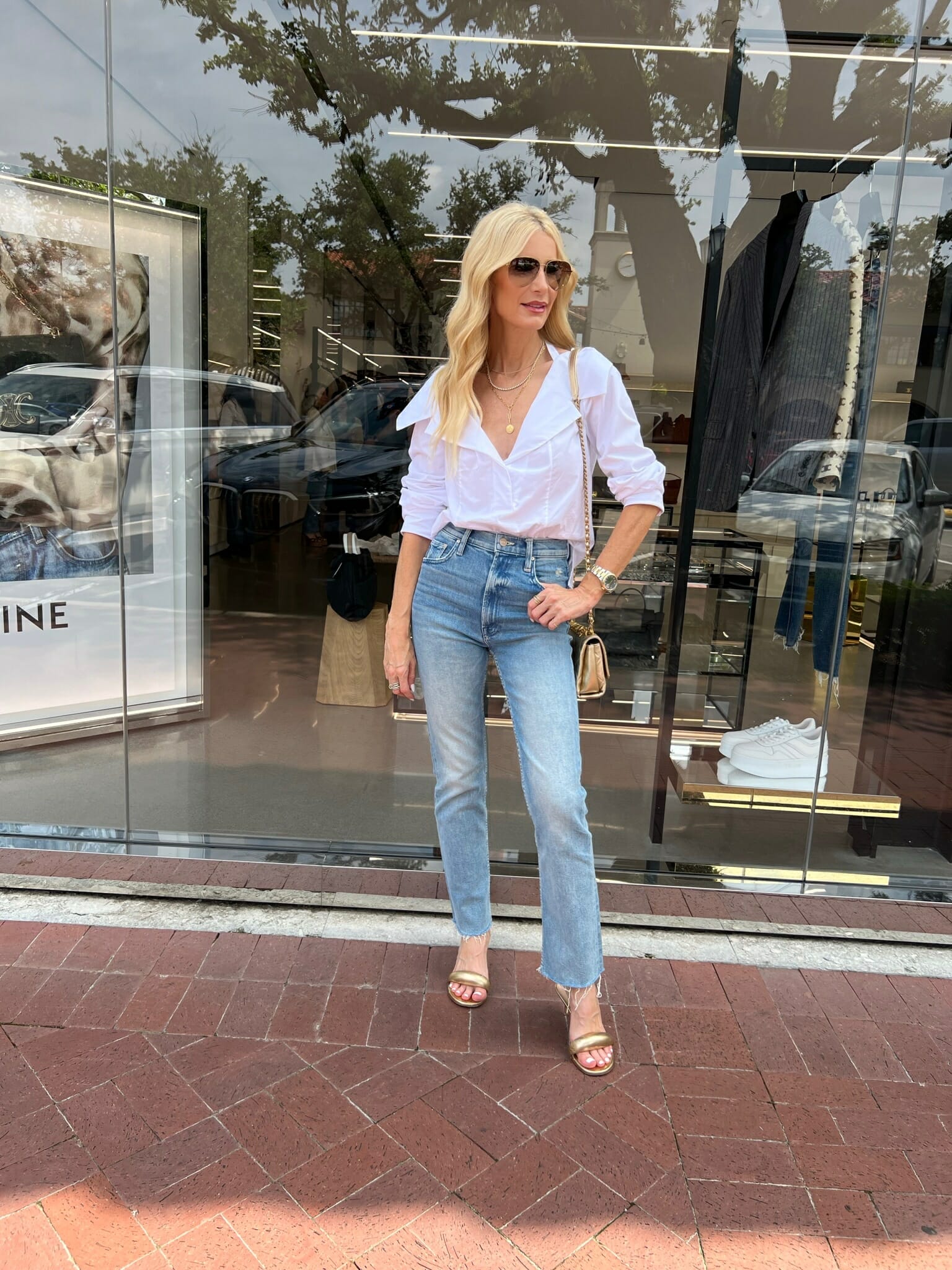 Dallas woman over 40 wearing off the shoulder top with crop jeans and gold accesories.