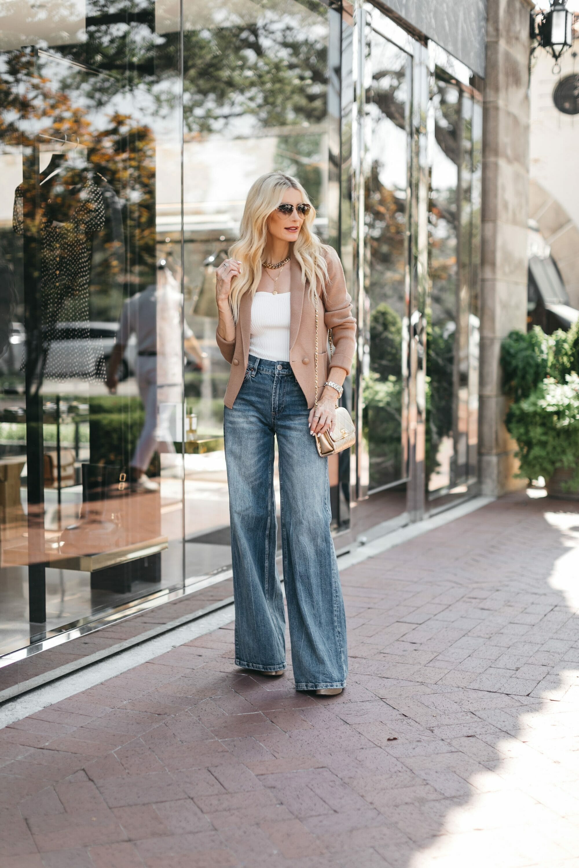 Dallas influencer for women over 40 wearing wide leg jeans and a tan blazer over a white bodysuit.