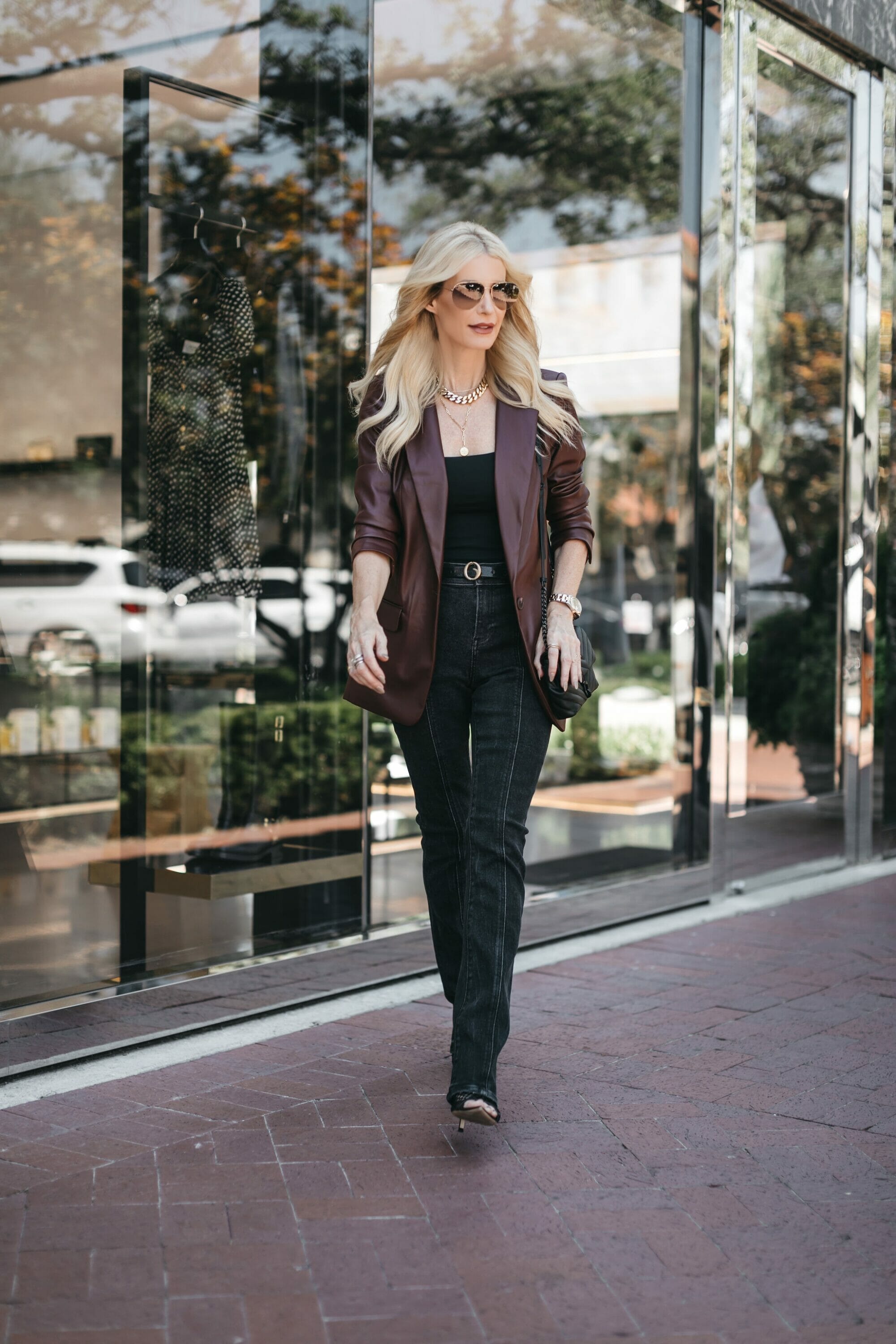 Over 40 fashion blogger wearing brown leather jacket with black faded deim and black heels.