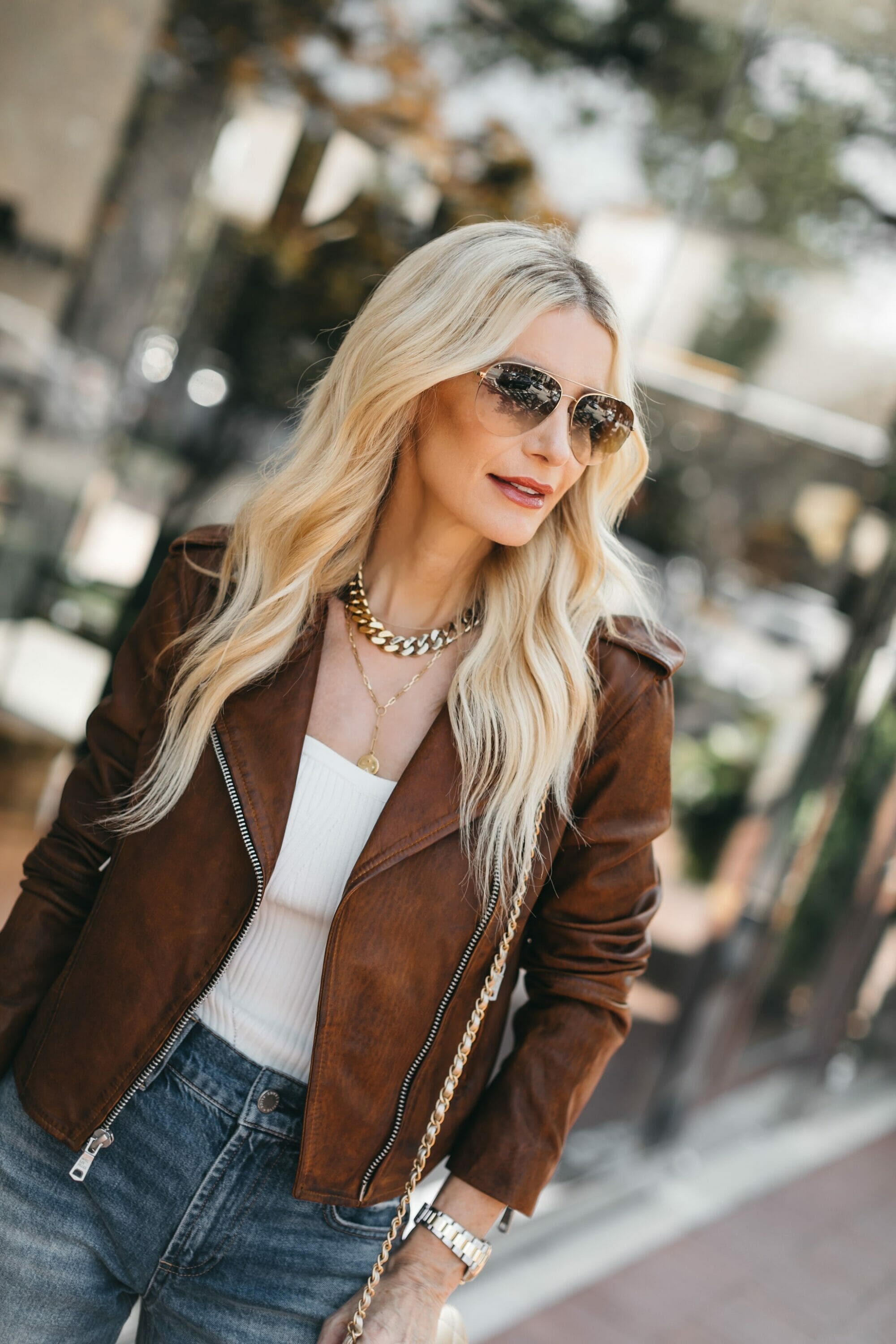Over 40 fashion blogger wearing brown faux leather jacket with wide leg jeans as one of August's top 5 best sellers.