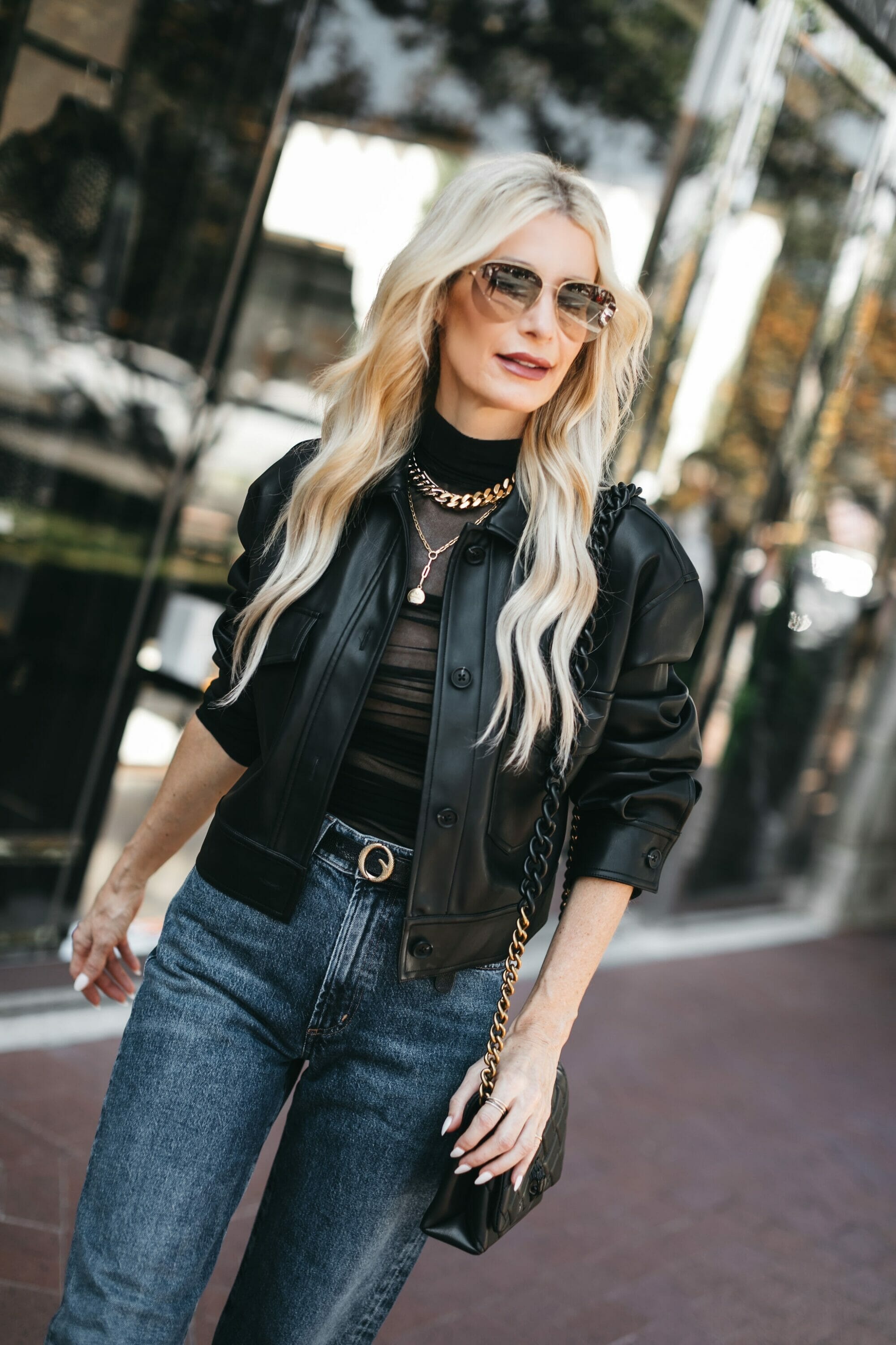 Dallas woman wears dark wash jeans with a sheer bodysuit and black leather blazer.