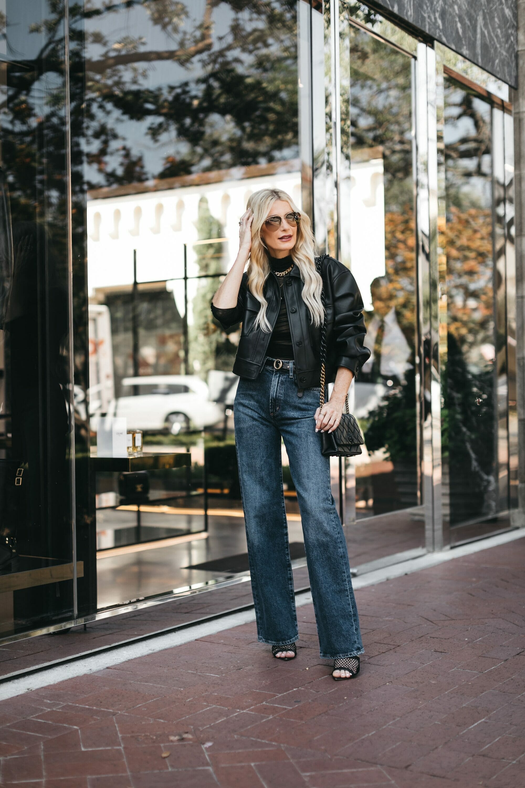 Dallas fashion influencer for women over 40 wears dark wash jeans with a leather bomber jacket as one of fall's hottest denim trends.