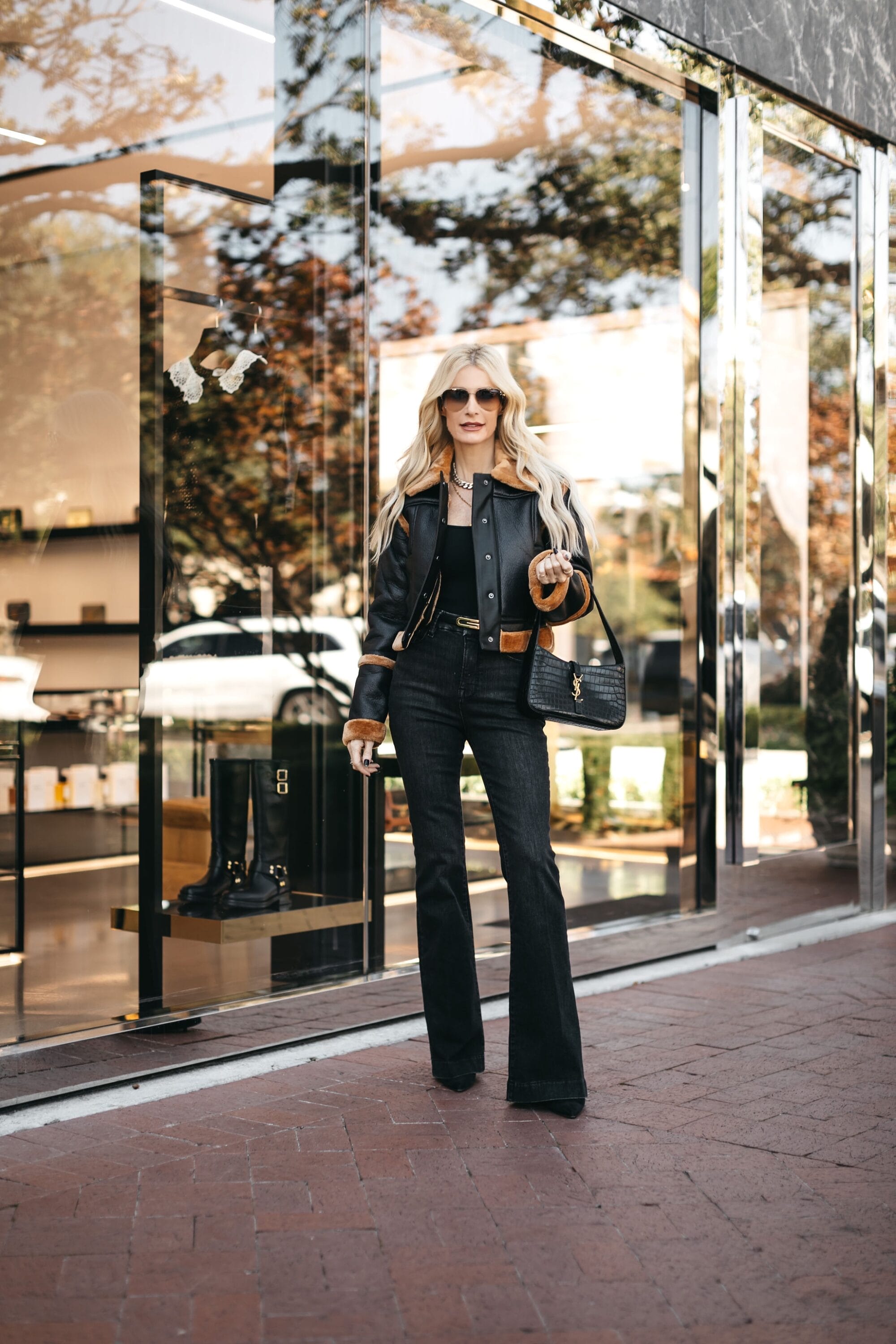 Dallas woman over 40 wearing black flare jeans with a black faux fur trimmed jacket.